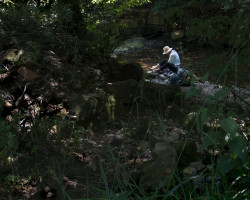 A pilgrim having lunch near a river. A pilgrim having lunch near a river
